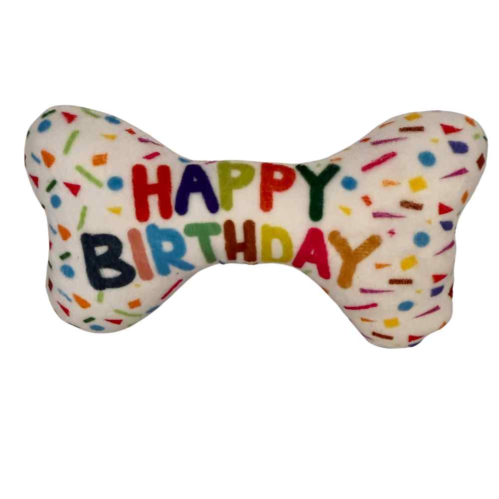 Spielzeug Happy Birthday in Knochenform  mit Schriftzug und Konfetti aufgedruckt.
